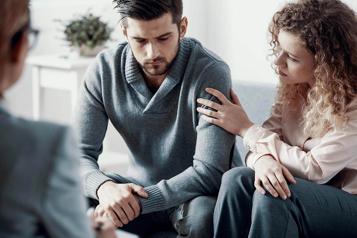 a man in outpatient alcohol addiction treatment is supported by a loved one in therapy