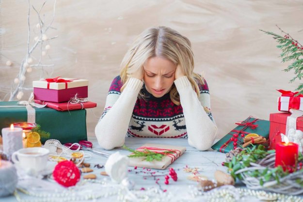 3 Tips to Manage Holiday Stress a person holds their head in a festive setting, possibly needing ways to manage holiday stress