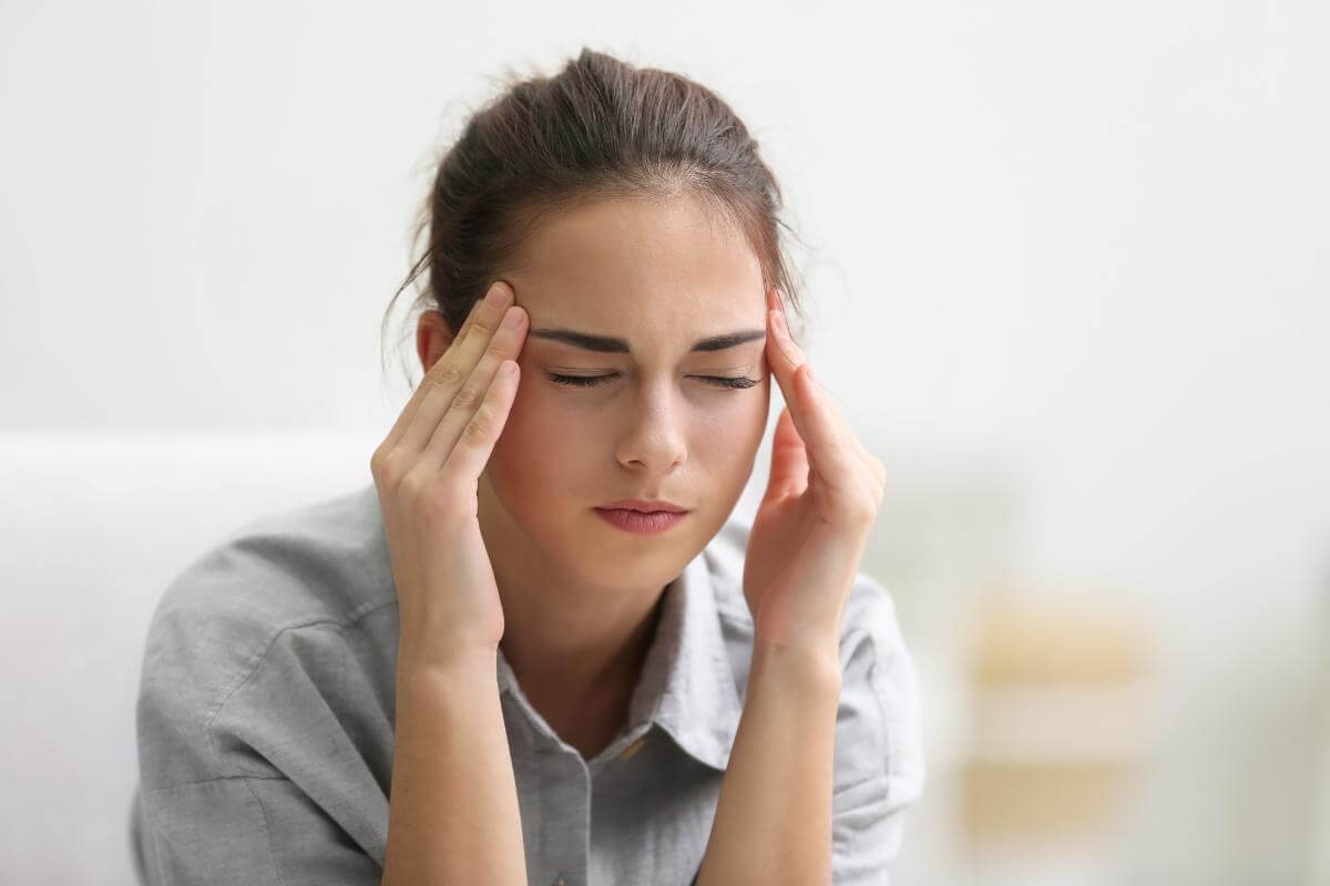Can Your Body Become Dependent On Alcohol person massaging temples while struggling with headache after becoming dependent on alcohol