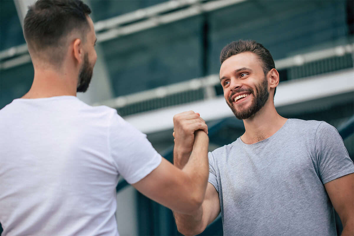 person in recovery shaking hands with smiling sober companion